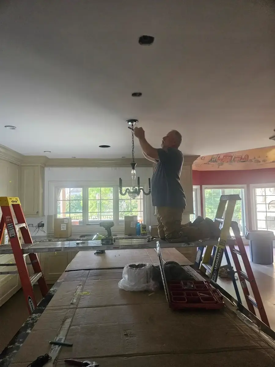 M&R electrician installing a chandelier in a residential kitchen